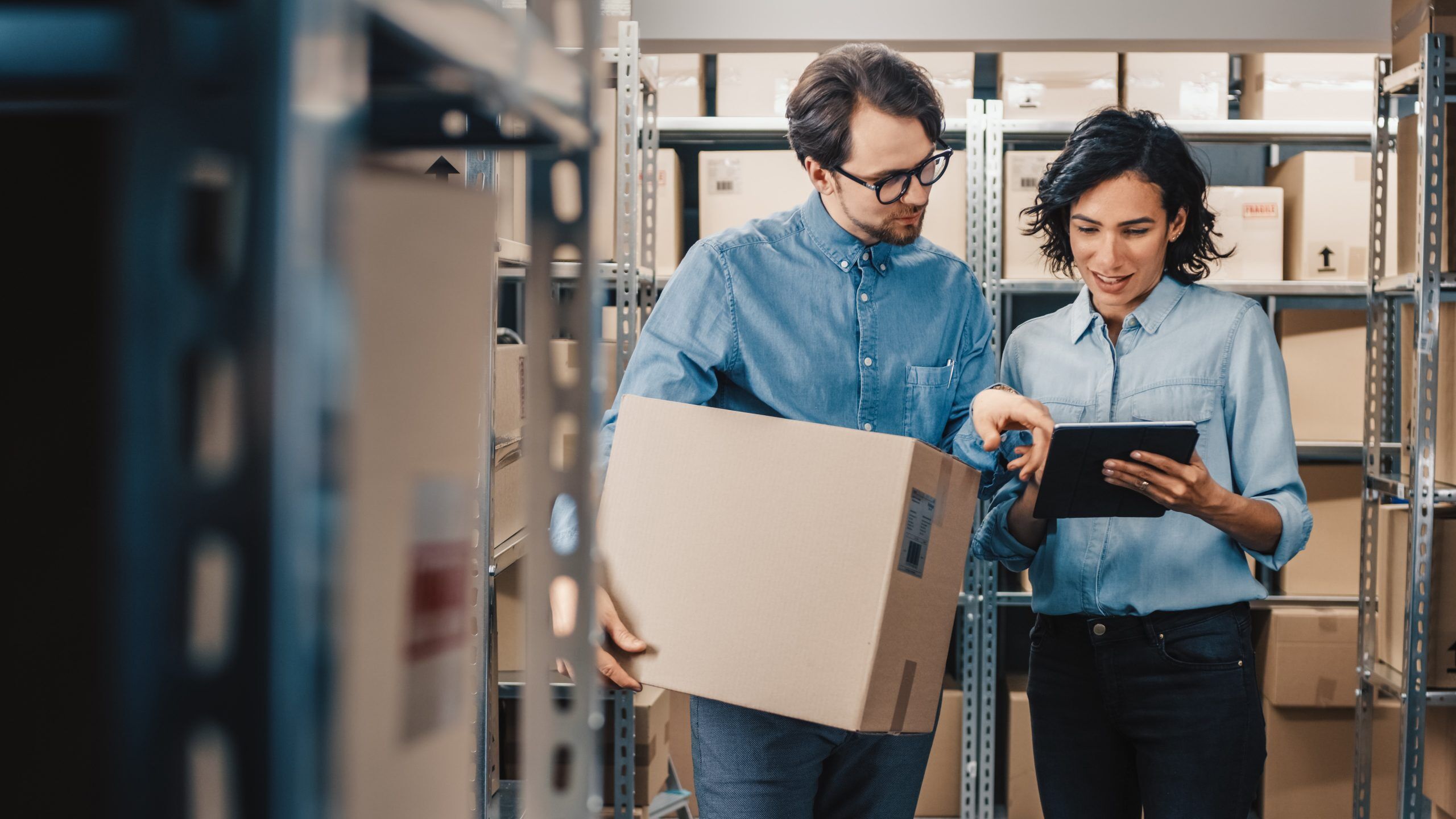 A photo of a man and a worman working together in a warehouse studying inventory