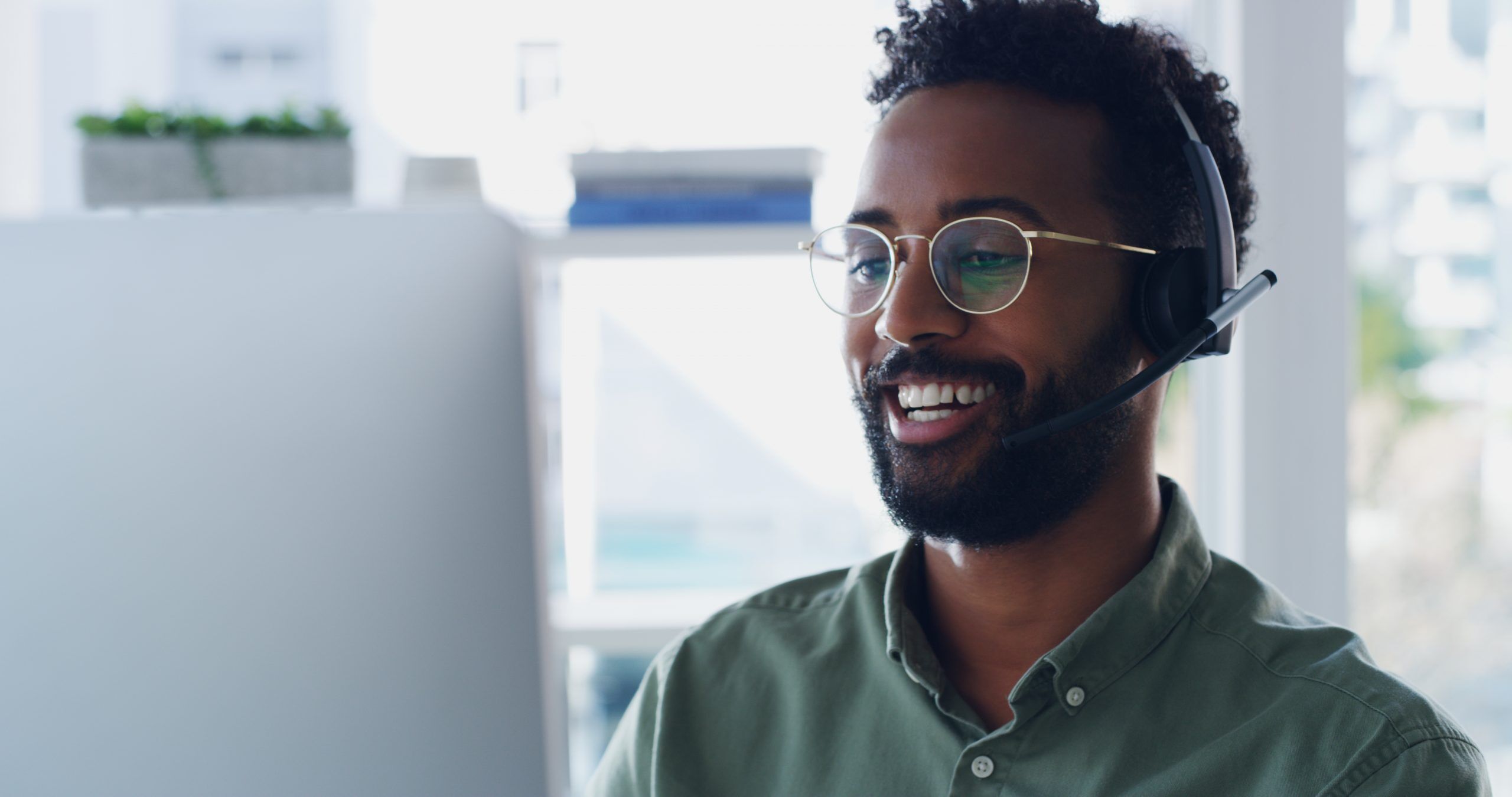 Photo of a man wearing a headset while talking to somone on they phone so he can provide technical support