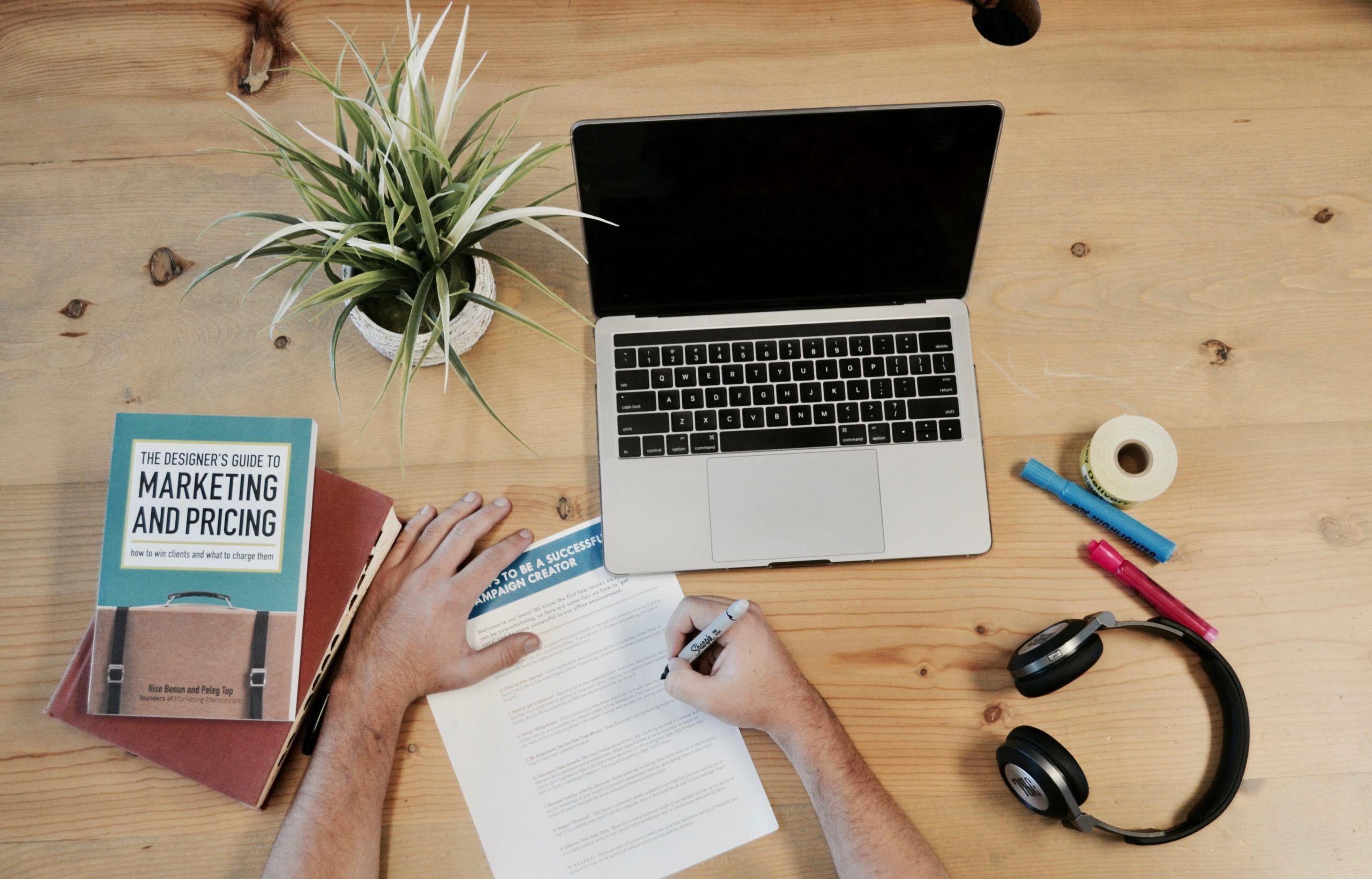 Desktop with a notepad, laptop, headphones and other work-related items